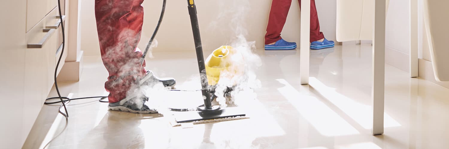 Eine Person in roter Kleidung reinigt mit einem Dampfreiniger.