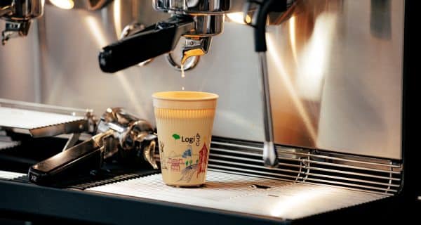 Ein Becher wird an einer Siebträgermaschine mit Kaffee befüllt.